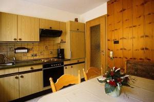 a kitchen with wooden cabinets and a table with flowers on it at Haus Margot Armbruster in Bad Rippoldsau-Schapbach