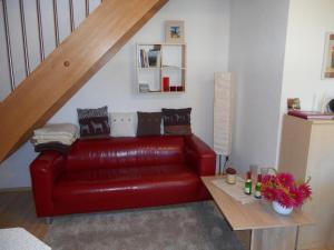 ein rotes Ledersofa im Wohnzimmer mit einer Treppe in der Unterkunft Rothers Ferienwohnung in Annaberg-Buchholz