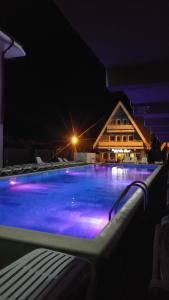 a swimming pool at night with a house in the background at Pensiunea La Castel - Piscina incalzita in Costinesti