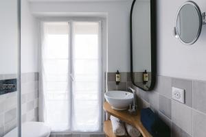 a bathroom with a sink and a mirror at Le Petit Cosy Hôtel in Paris