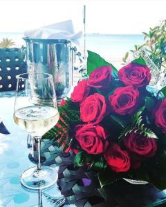 a glass of wine next to a bouquet of red roses at Amare&Mare Apartment in Sutomore