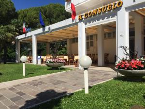 ein Gebäude mit zwei Fahnen im Gras in der Unterkunft Hotel Consuelo in Lignano Sabbiadoro