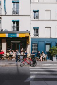 un grupo de personas sentadas en mesas fuera de un edificio en Le Petit Cosy Hôtel, en París