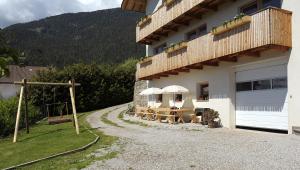 a building with tables and umbrellas outside of it at Rumpelehof in Villandro