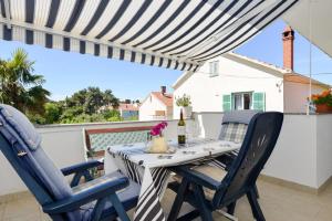 a patio table with two chairs and a bottle of wine at Apartment Vesna in Zadar