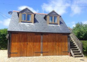 a large wooden garage with a staircase and a house at Pump View in Weymouth