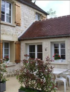 a house with a table and chairs in front of it at Les Rainettes in Coye-la-Forêt