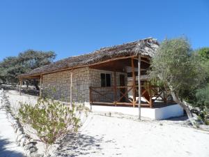 a small house with a thatched roof on a beach at Shangri-la Lodge in Ambatomilo