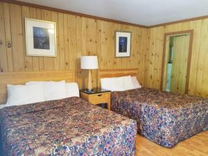 two beds in a hotel room with wooden walls at Seven Dwarfs Cabins - Brown Cabins in Lake George