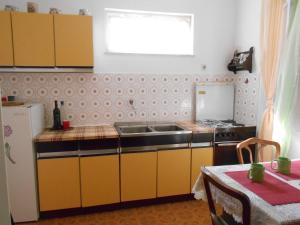 a kitchen with yellow cabinets and a sink and a table at Apartments Ema in Šibenik