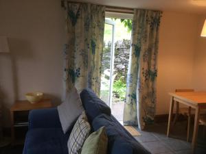 a living room with a blue couch and a sliding glass door at Oban Seil Farm The Bothy in Clachan