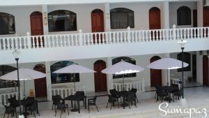 梅爾加的住宿－Suite Sumapaz Hotel，一座配有桌椅和白色遮阳伞的建筑