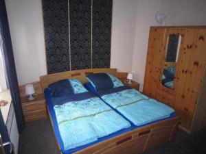 a bedroom with a bed with blue sheets and blue pillows at Ferienhaeuser-MoJe-1 in Dornum