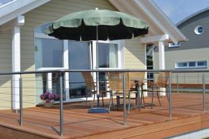 eine Terrasse mit Stühlen und einem Regenschirm auf einem Haus in der Unterkunft "Hiddensee" in Wiek auf Rügen 