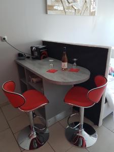 una mesa con 2 sillas rojas y una botella de vino en Port nature, en Cap d'Agde