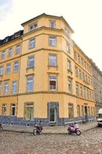德勒斯登的住宿－Schoene-3R-Fewo-Dresden-Neustadt-L12，一座黄色的大建筑,前面停有两辆摩托车