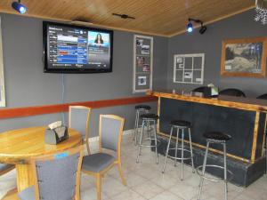 a bar with stools and a tv on the wall at Alcan Motor Inn in Haines Junction