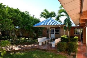 a patio with two benches and a blue and white umbrella at Hotel Campestre Kosta Azul in Villavicencio