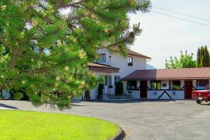 un arbre devant une maison avec un camion rouge dans l'établissement Bavarian Orchard Motel, à Creston