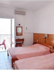 a bedroom with two beds and a desk and a window at Hotel Christina in Skiathos