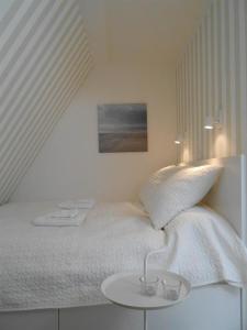 a white bedroom with a bed and a small table at Haus-LIV-Appartement-Duene in Westerland (Sylt)