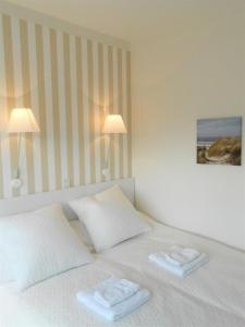 Una cama blanca con dos toallas encima. en Haus-LIV-Appartement-Sand en Westerland