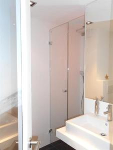 y baño con lavabo y ducha con espejo. en Haus-LIV-Appartement-Sand en Westerland