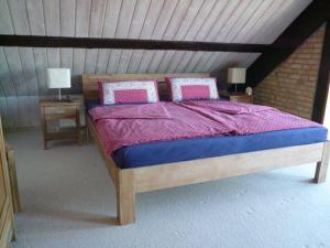 Schlafzimmer mit einem Holzbett mit rosa und blauer Bettwäsche in der Unterkunft Ferienhaus mit Kamin & Sauna Ostsee-Südstrand in Pelzerhaken