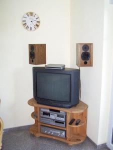 a tv on a stand with speakers and a clock at Zur-alten-Schmiede-II-Wohnung-unten-II in Boltenhagen