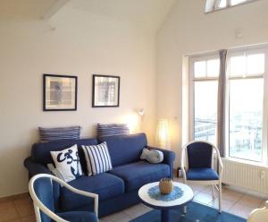a living room with a blue couch and two chairs at Ferienwohnung-Meeresblick-Rerik in Rerik