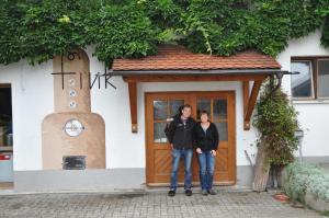 2 personnes debout devant une maison dans l'établissement Ferienhof-Fink-Ferienwohnung-Sonnenblume, à Opfenbach