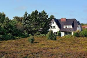 a white house on top of a hill with trees at Sylt-Ferienhaus-fuer-gehobene-Ansprueche in Erlangen