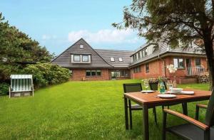 una mesa y sillas en un patio con una casa en Strandlaeufer-Landhaus-Tadsen, en Westerland