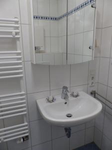 ブルハーフェにあるFerienhaus-Mellumringの白いバスルーム(シンク、鏡付)
