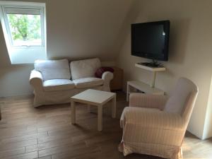 ein Wohnzimmer mit einem Sofa und einem TV in der Unterkunft Huus Windroos  Wohnung 2 in Ditzum