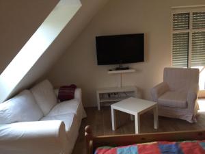 ein Wohnzimmer mit einem weißen Sofa und einem TV in der Unterkunft Huus Windroos  Wohnung 2 in Ditzum