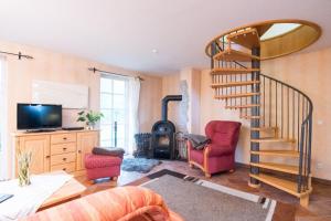 a living room with a spiral staircase and two chairs at Ferienhaus Jan in Nordstrand