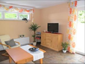 a living room with a tv on a cabinet and a table at Ferienwohnung im Rosental in Andernach