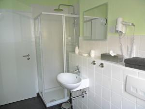 a white bathroom with a shower and a sink at Ferienwohnung im Rosental in Andernach