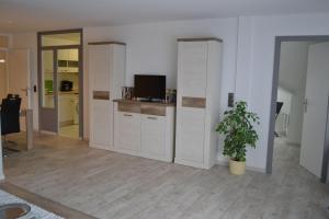 una sala de estar con armarios blancos y una maceta. en App-Duenenblick-Haus-Loreley en Sankt Peter-Ording