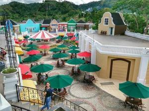 a woman standing on a balcony with a bunch of green umbrellas at Olivine House in Bandar Lampung