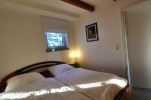 Schlafzimmer mit einem Bett mit weißer Bettwäsche und einem Fenster in der Unterkunft Gesindehaus Charis in Kippenheim