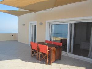 a balcony with a table and red chairs on it at Viva B&B in Anavyssos
