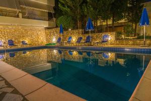 a swimming pool with chairs and blue umbrellas at Geni Garden Apartments in Yenion