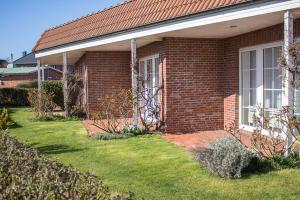 a red brick house with a grass yard at Pension KRUSE in Büsum