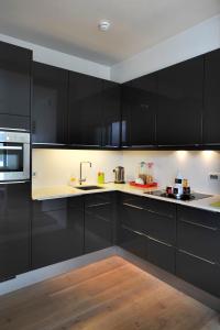 a kitchen with black cabinets and a wooden floor at B&B Kava in Antwerp