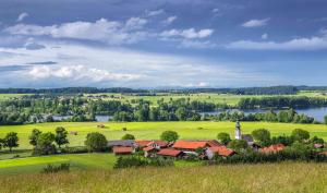 a village in the middle of a green field with a lake at GADEN Apartment - Hotel in Waging am See