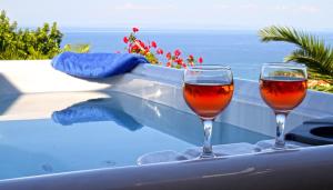 two glasses of wine sitting on the edge of a swimming pool at Villa Contessa in Vasilikos