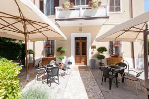 un patio esterno con tavoli, sedie e ombrelloni di Hotel Gardenia a Forlì