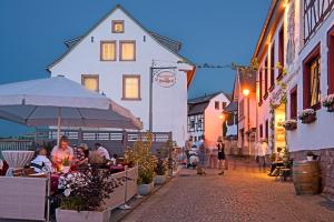 a group of people sitting at tables on a street at Hotel Zum Burggraf in Neuleiningen